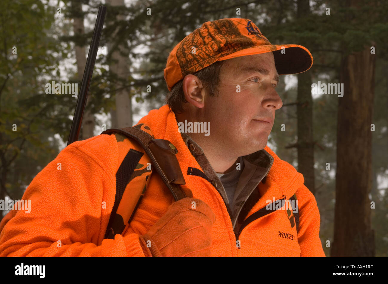 PORTRAIT OF DEER HUNTER IN BLAZE ORANGE WITH RIFLE ON HIS BACK IN FOGGY