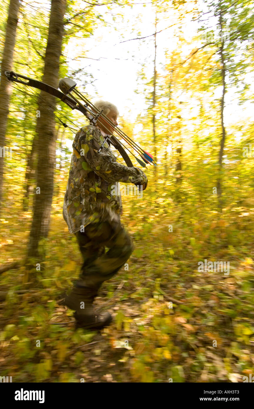 A WOMAN BOW HUNTER HUNTING WHITE TAIL DEER WALKS THROUGH THE WOODS WITH