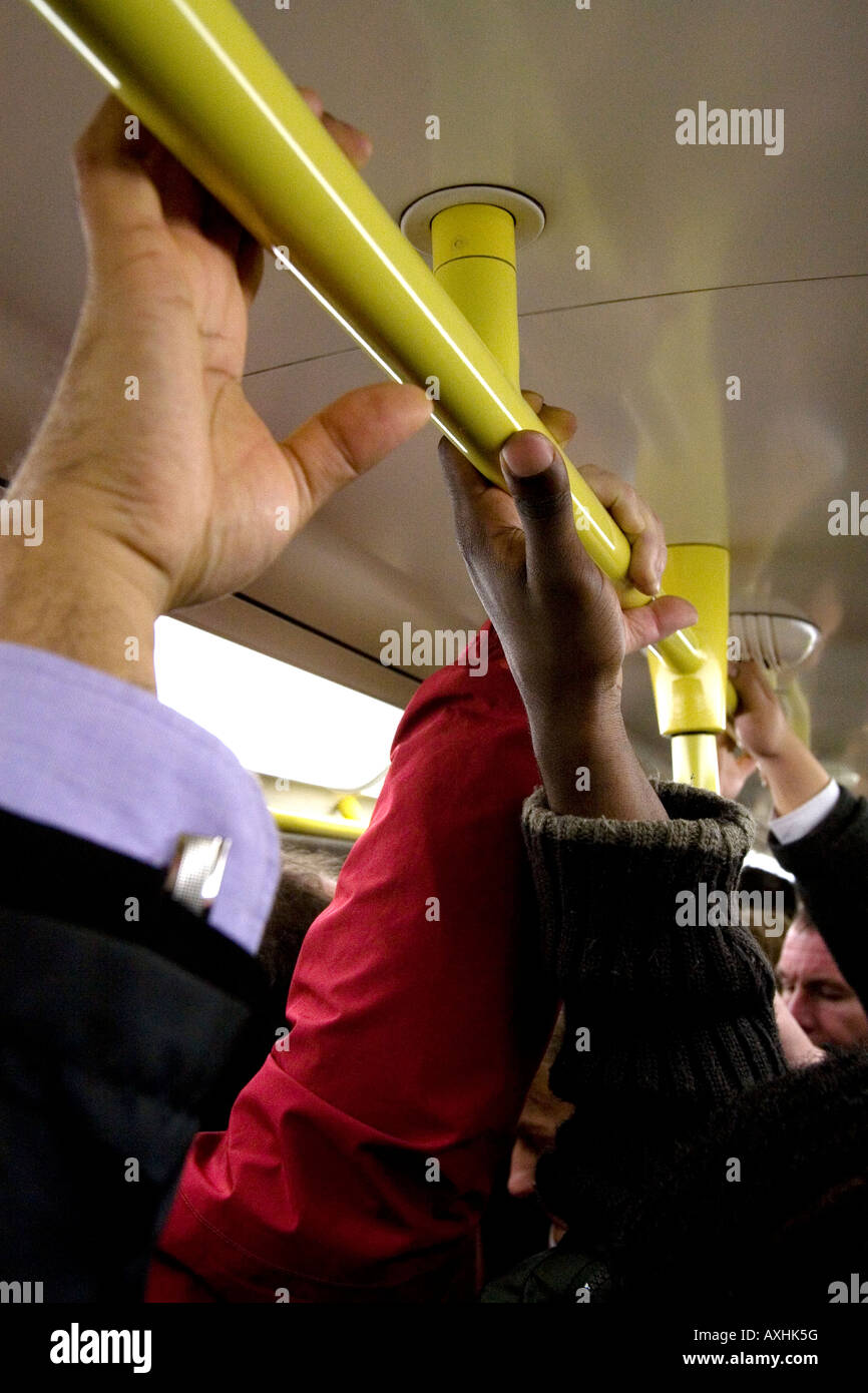 People holding onto the hand rail on a London Underground Tube during morning rush hour. Stock Photo