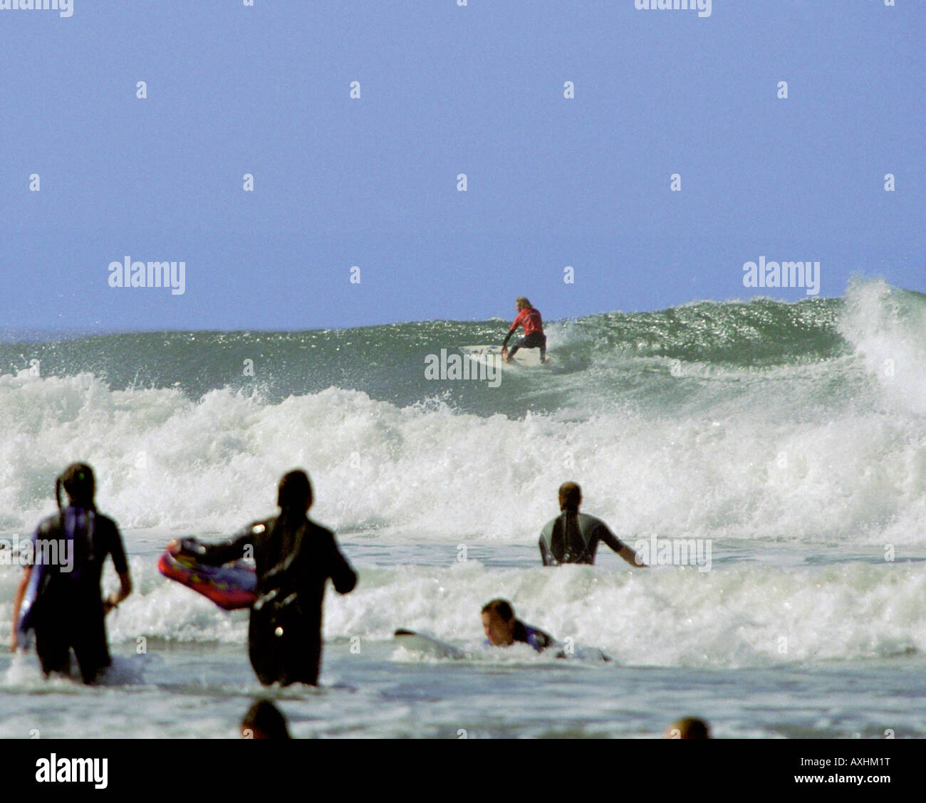 Surfer watched by surfers & boogie boarders flies along the wall of a ...