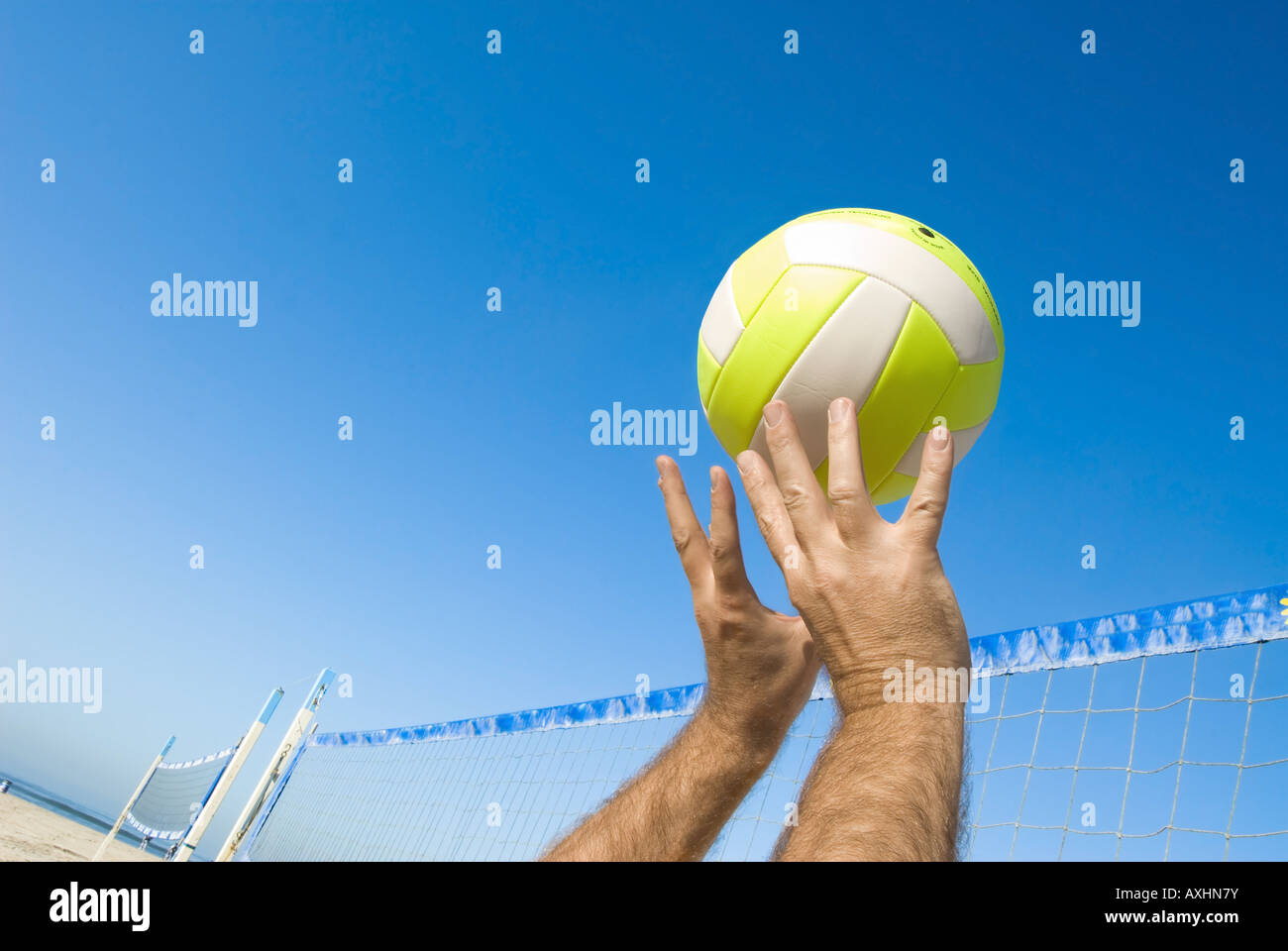 A volleyball player lobs a ball during a game at the beach Stock Photo