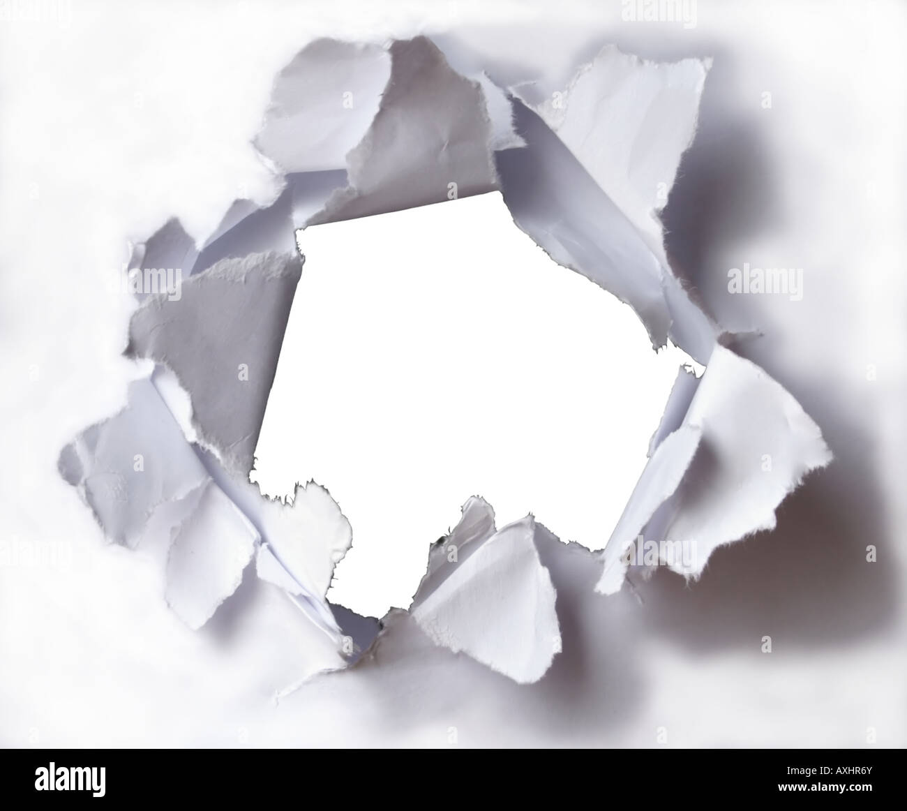 Close-up of large hole in the white paper (background). Stock Photo