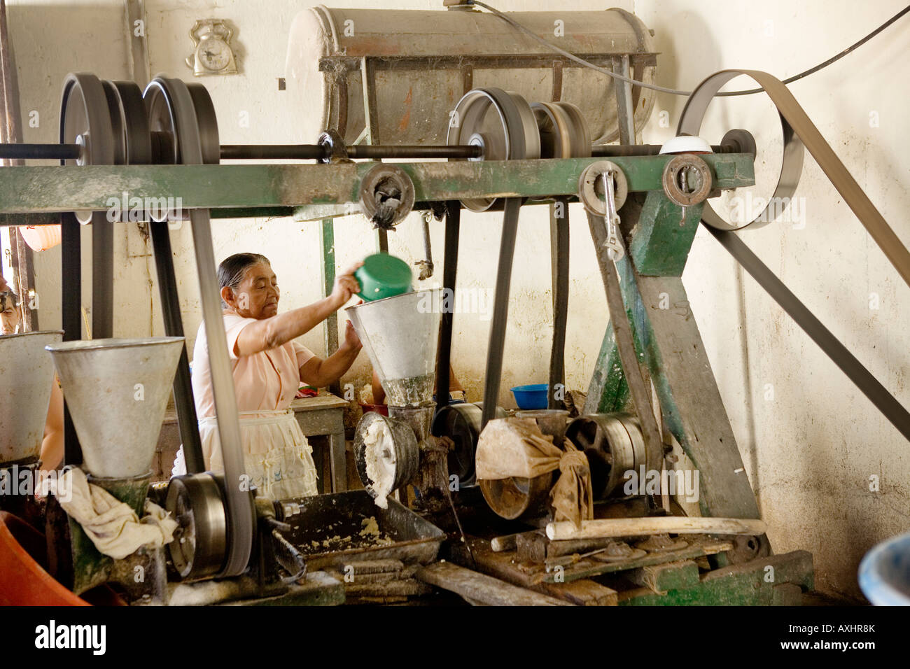 Elderly woman using community molina mill for grinding corn grain and coffee in Suchitoto El Salvador Stock Photo