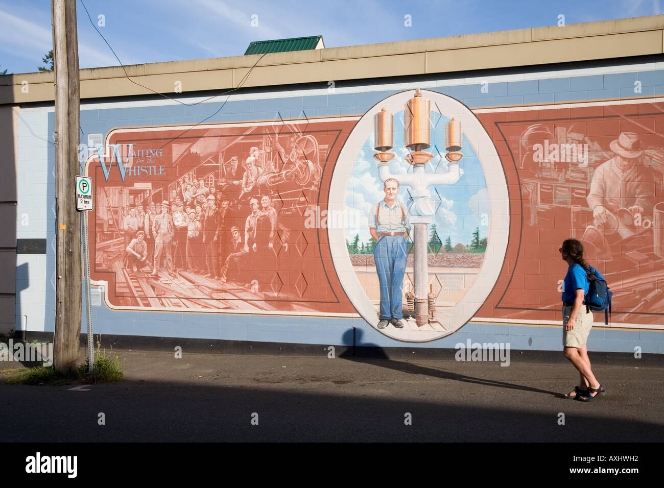 Woman looking at mural railroad lumbermen on wall in Chemainus Canada Stock Photo