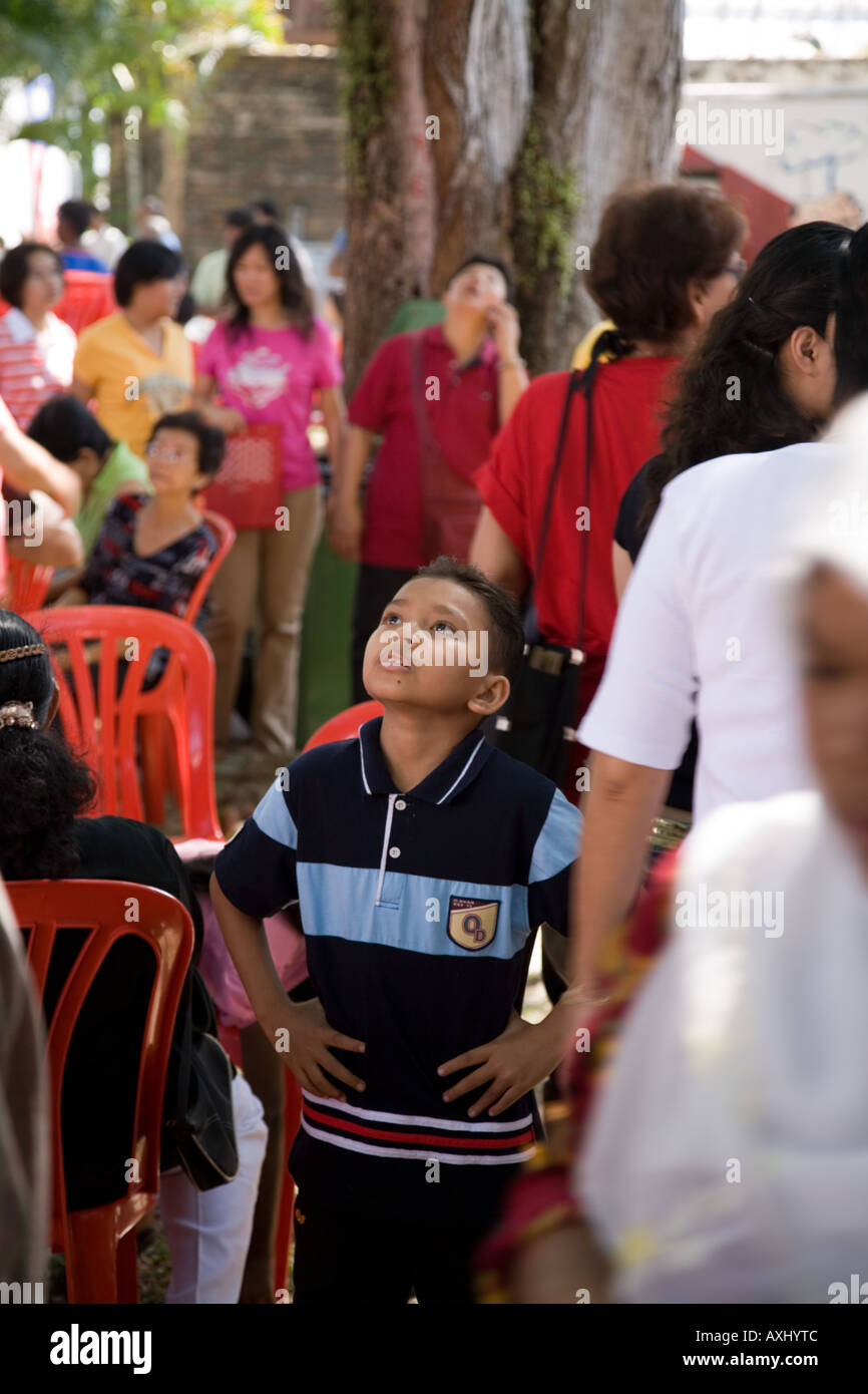 Child looks up to the tree tops during Chinese New Year celebrations. Fort Cornwallis. Georgetown. Penang. Malaysia. Stock Photo