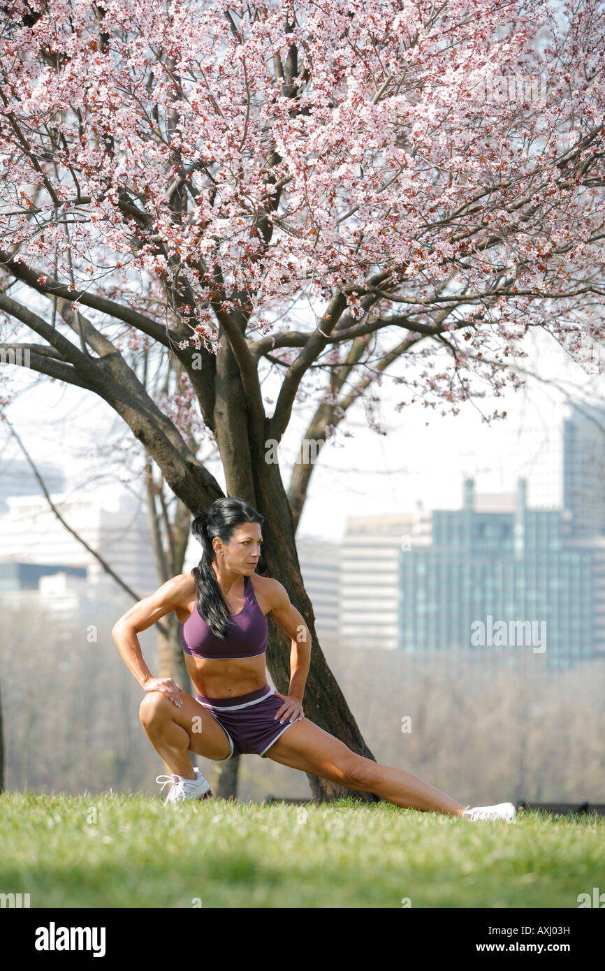 Woman athletic age 45 stretching outdoors, Cherry blossoms