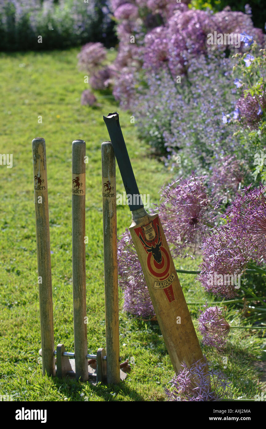 A SET OF STUMPS AND CRICKET BAT ALONGSIDE A FLOWER BED WITH ALLIUM CRISTOPHII IN THE GARDEN AT MANOR FARM SOMERSET Stock Photo
