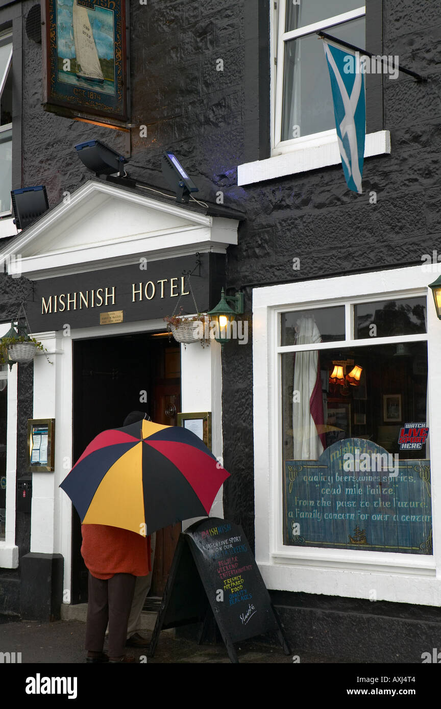Tourists looking in on Mishnish pub and hotel on seafront, Tobermory, Isle of Mull, west coast of Scotland, United Kingdom Stock Photo