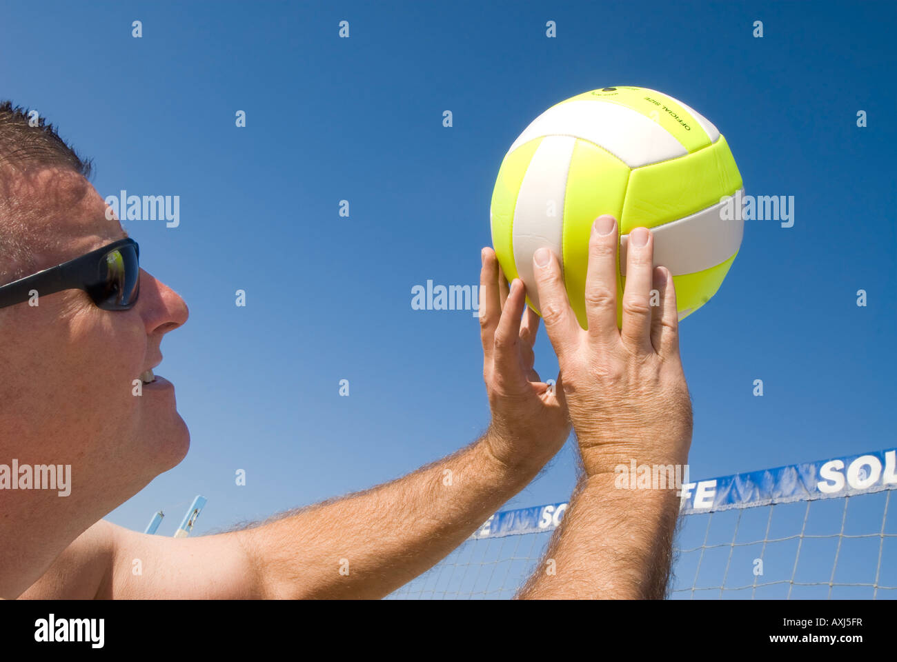 A volleyball player lobs a ball during a game at the beach Stock Photo