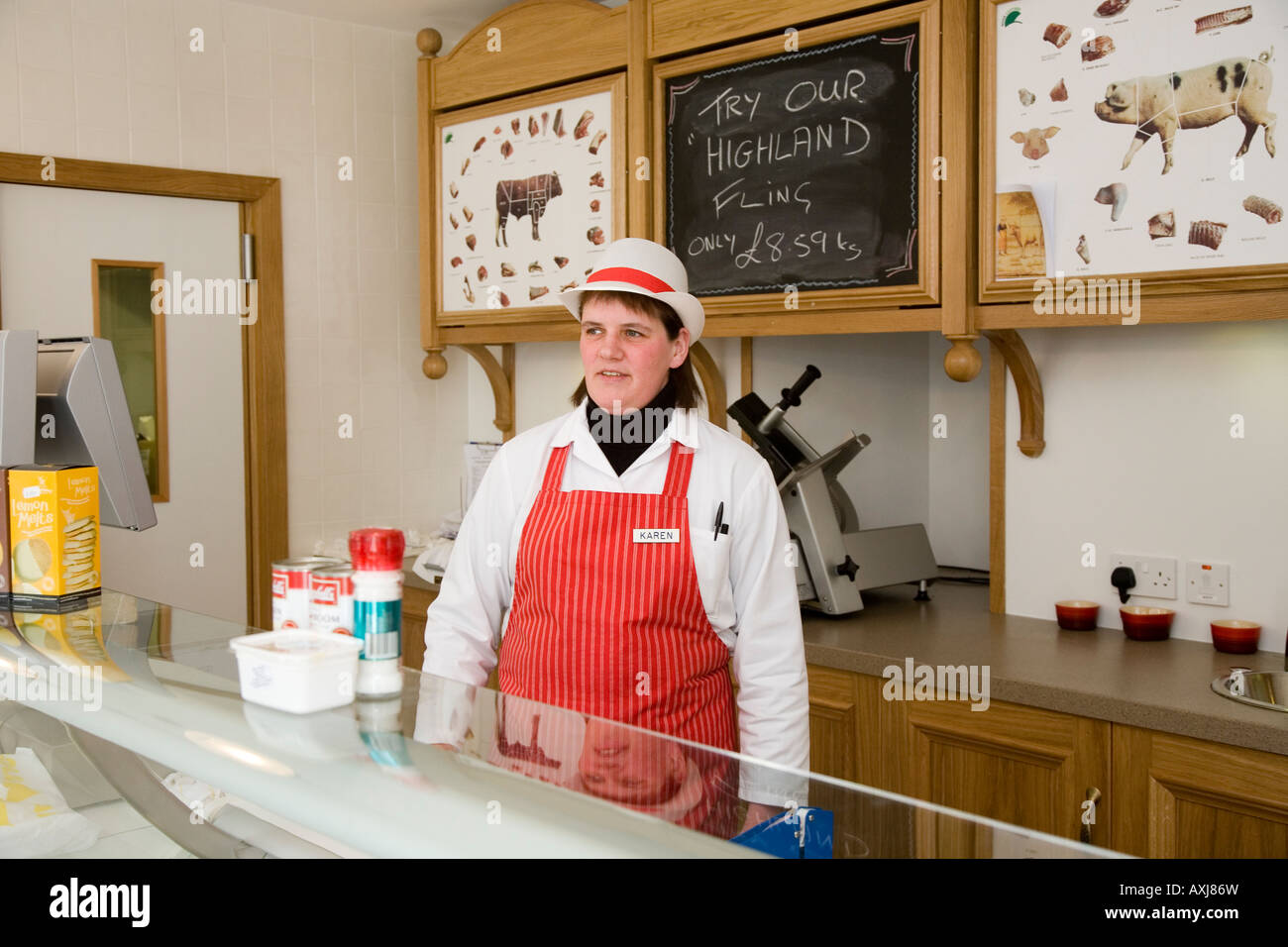 Butchers Assistant in Shop wearing Red Apron  W Irvine Butchers Blairgowrie, Scotland uk Stock Photo
