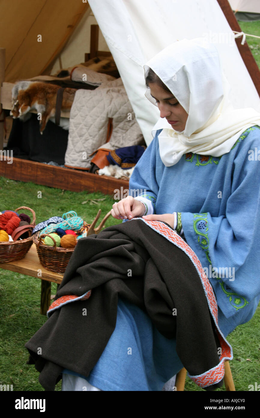 A woman is sewing at a Saxon camp. Stock Photo