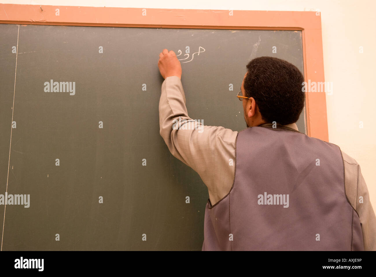 Teacher writing on blackboard during adult education class in Arabic at the Islamic Arts and