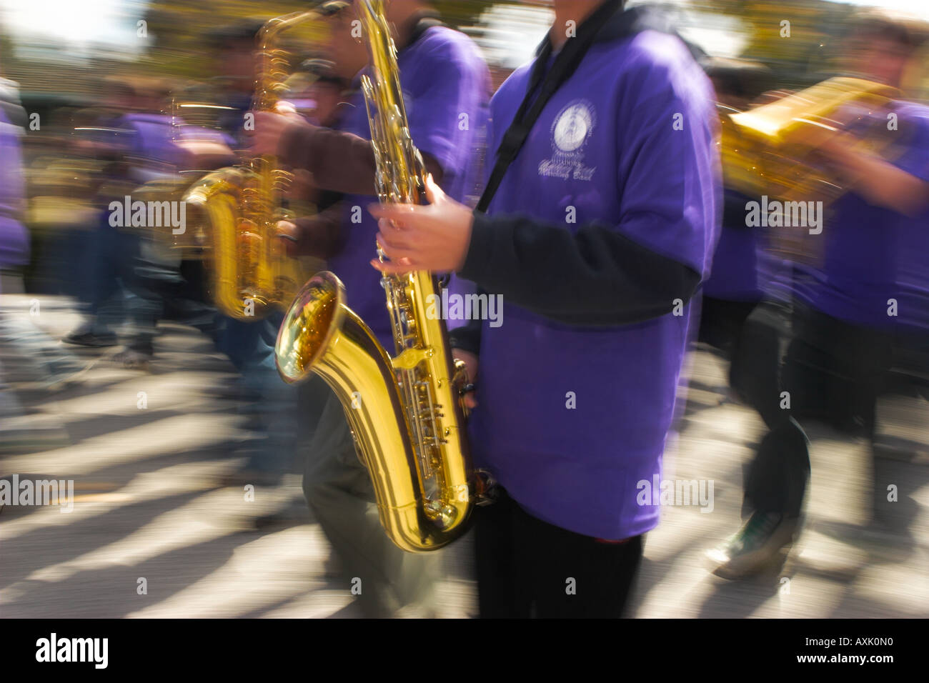 people students marching in parade blowing gold instrument trumpet in purple uniform event celebration music sound listen horn Stock Photo