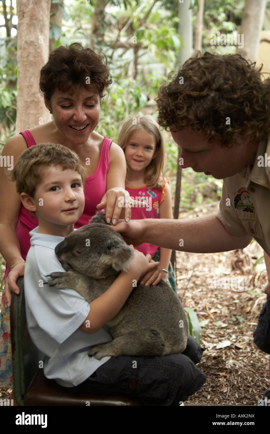 Young boy child holding a Koala bear in Lone Pine Koala Sanctuary wildlife reserve zoo Brisbane Queensland QLD Australia NAOH Stock Photo