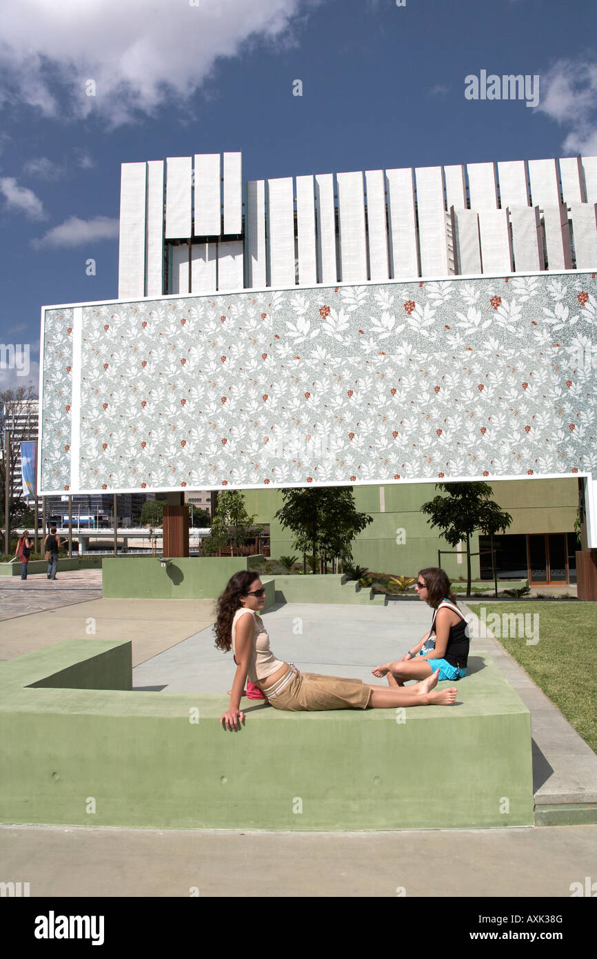 Two women sitting outside State Library building in sumer sunshine in Brisbane Queensland QLD Australia Stock Photo