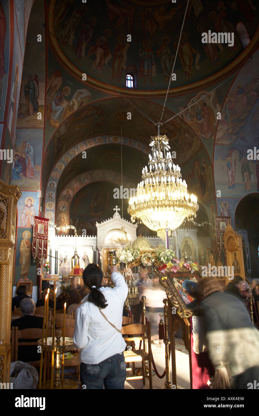 Women worshipper lighting candle kissing icon before Easter Good Friday