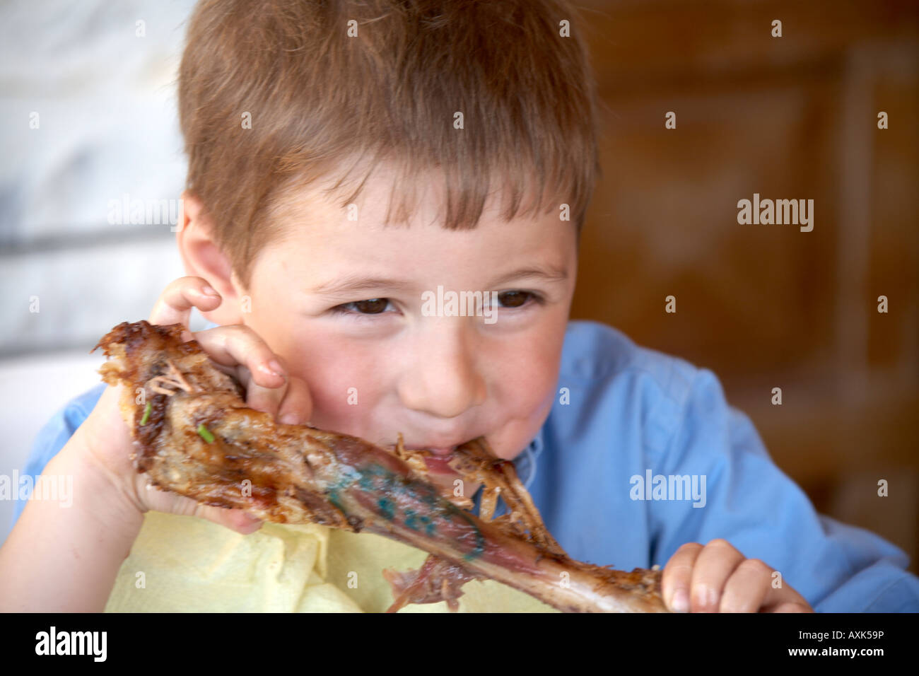 Young caucasian boy child carniverous carnivore eating bone of lamb or