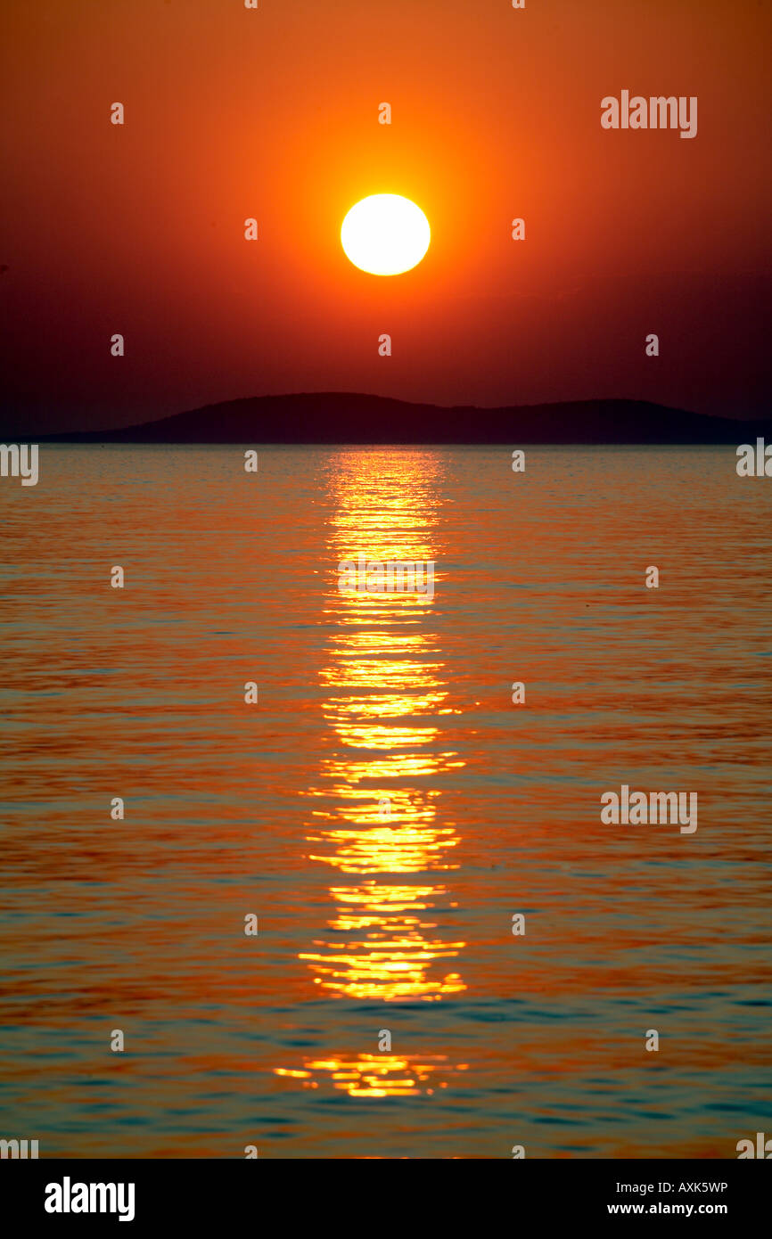 Red orange and gold colours of the sun setting into the sea above ...
