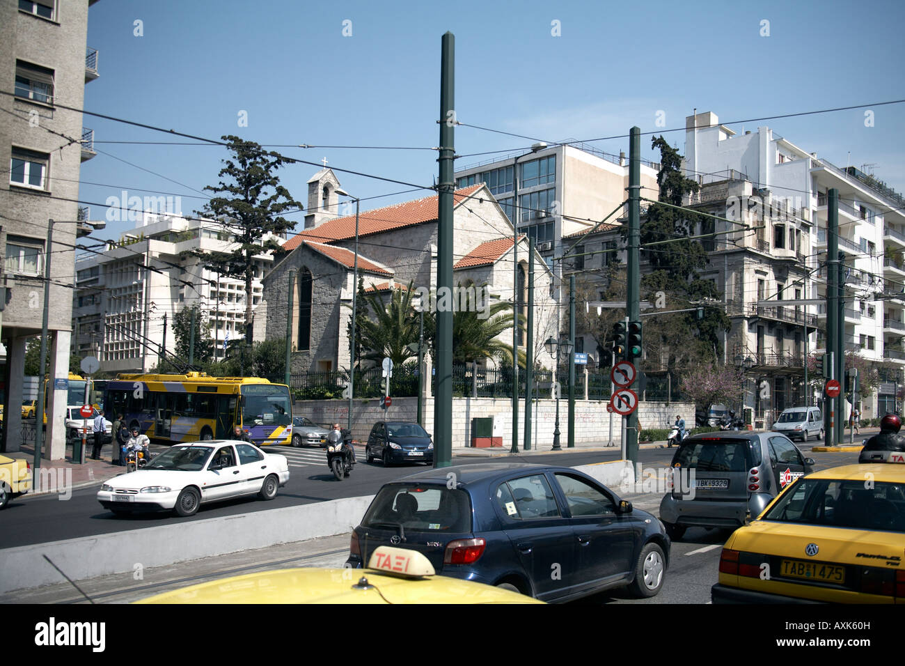 Church and buildings obscured by tram cables with traffic on Andrea Singrou street in Athens or Athini Greece Stock Photo