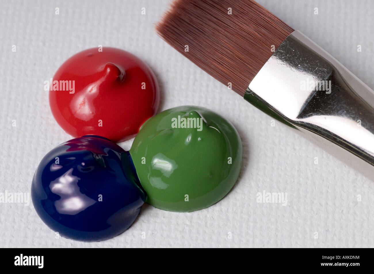 red and green and blue paint blob on canvas with brush near by closeup Stock Photo