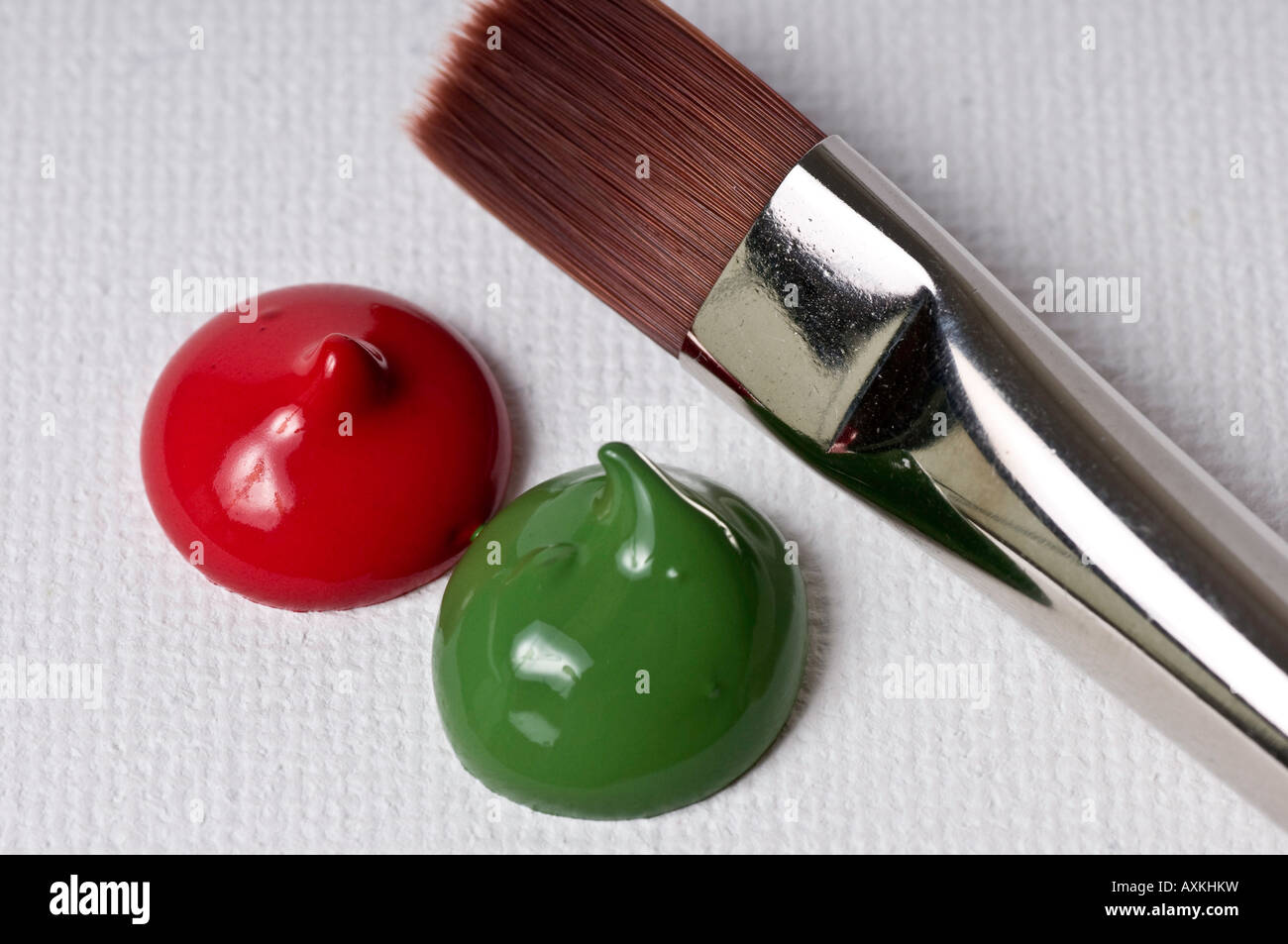 red and green paint blob on canvas with brush near by closeup Stock Photo