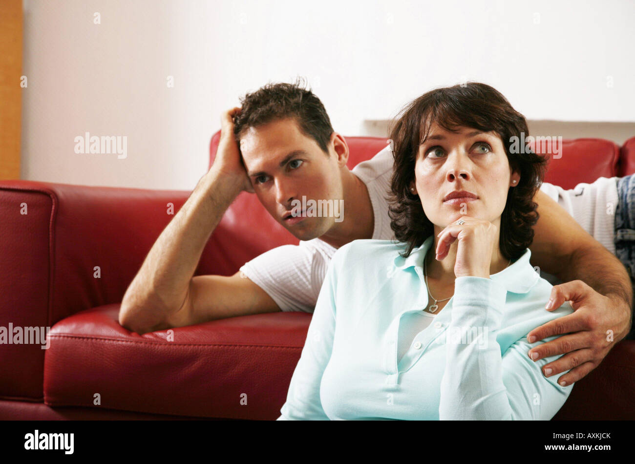 Symbols of Partnership A young woman tries to tell her partner something while he is watching tv Stock Photo