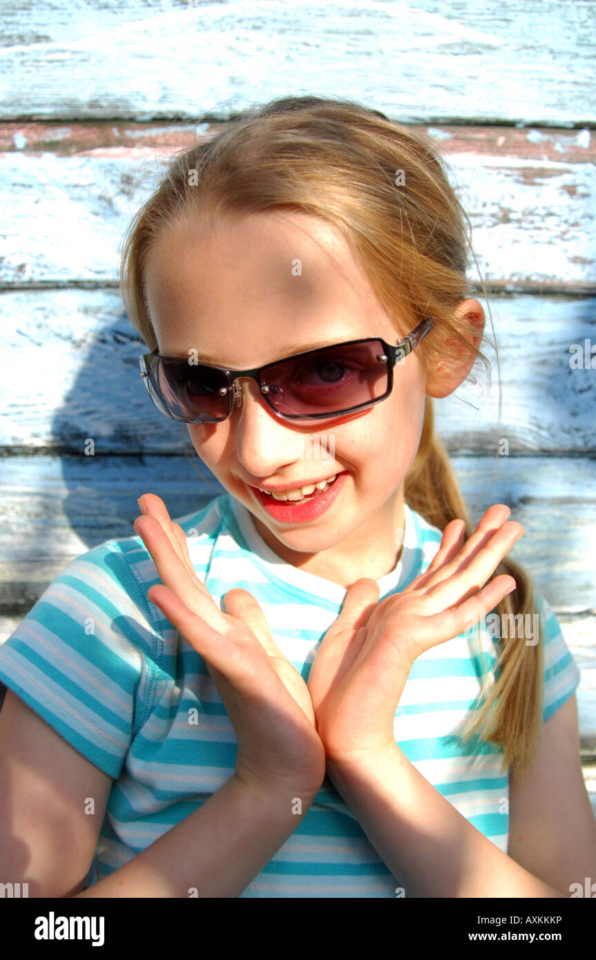 Photograph of young girl posing in the sunshine with sunglasses on family summer holiday UK. Stock Photo
