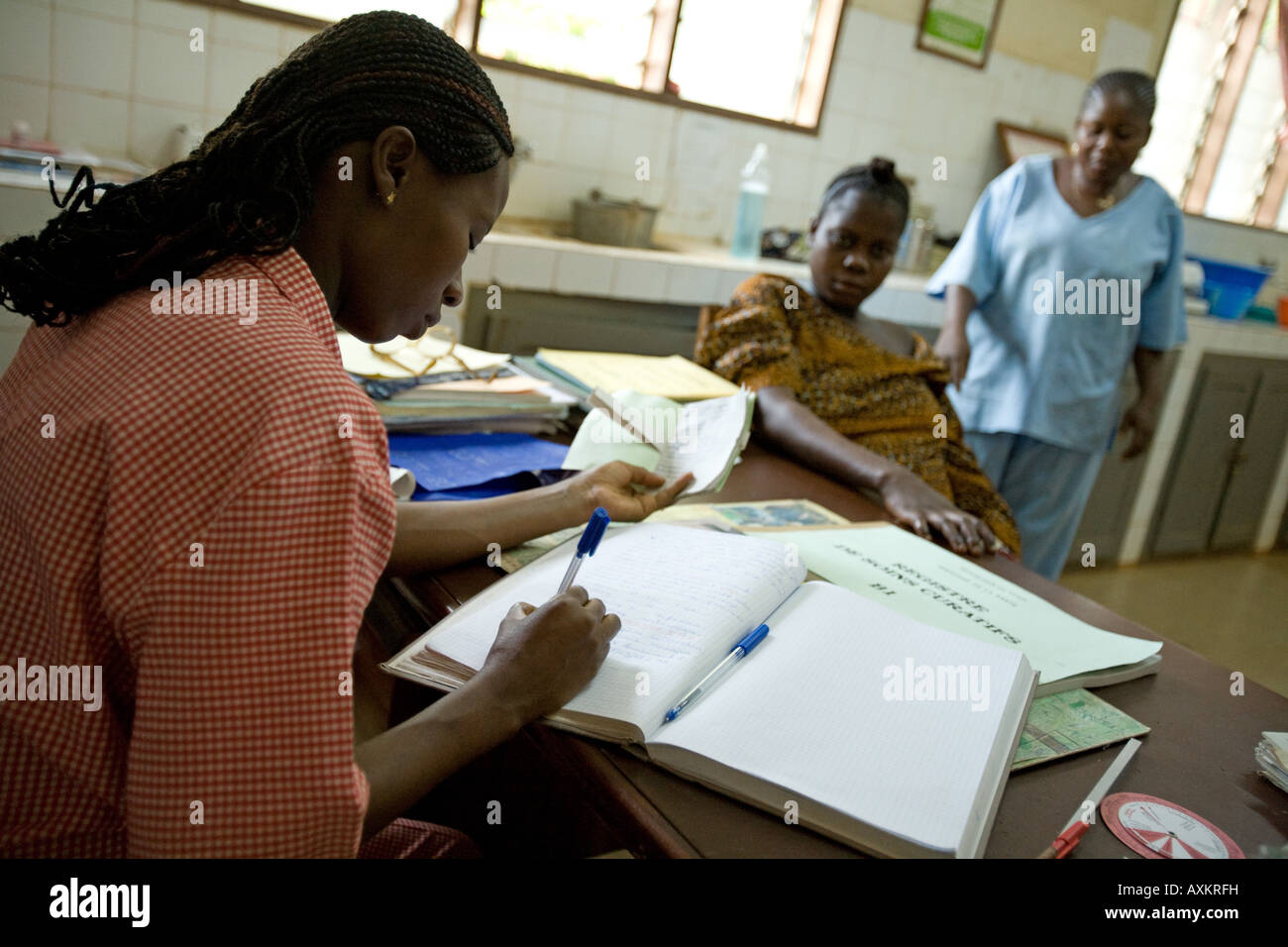 A health worker fills in a registry with medical information during a consultation with a pregnant woman, Benin, Africa Stock Photo