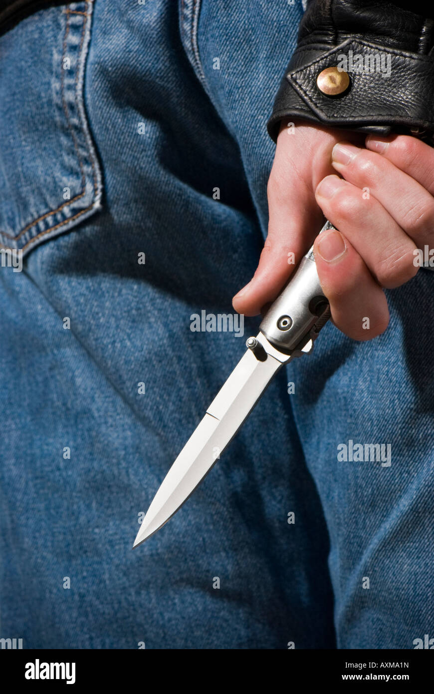 Knife crime - waiting with knife hidden behind back Stock Photo