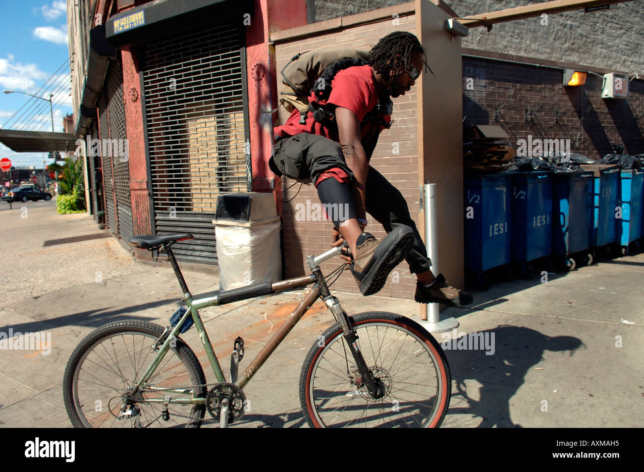 Bike messenger dismounts to make deliveries and pick ups in the trendy Meatpacking District in NYC Stock Photo