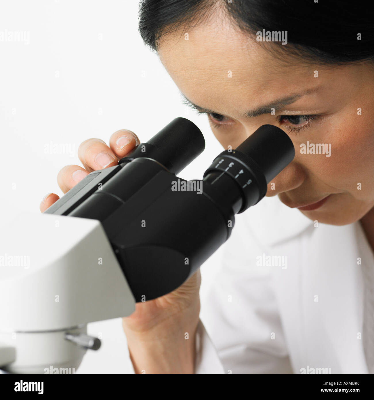 Close up of woman looking in microscope Stock Photo