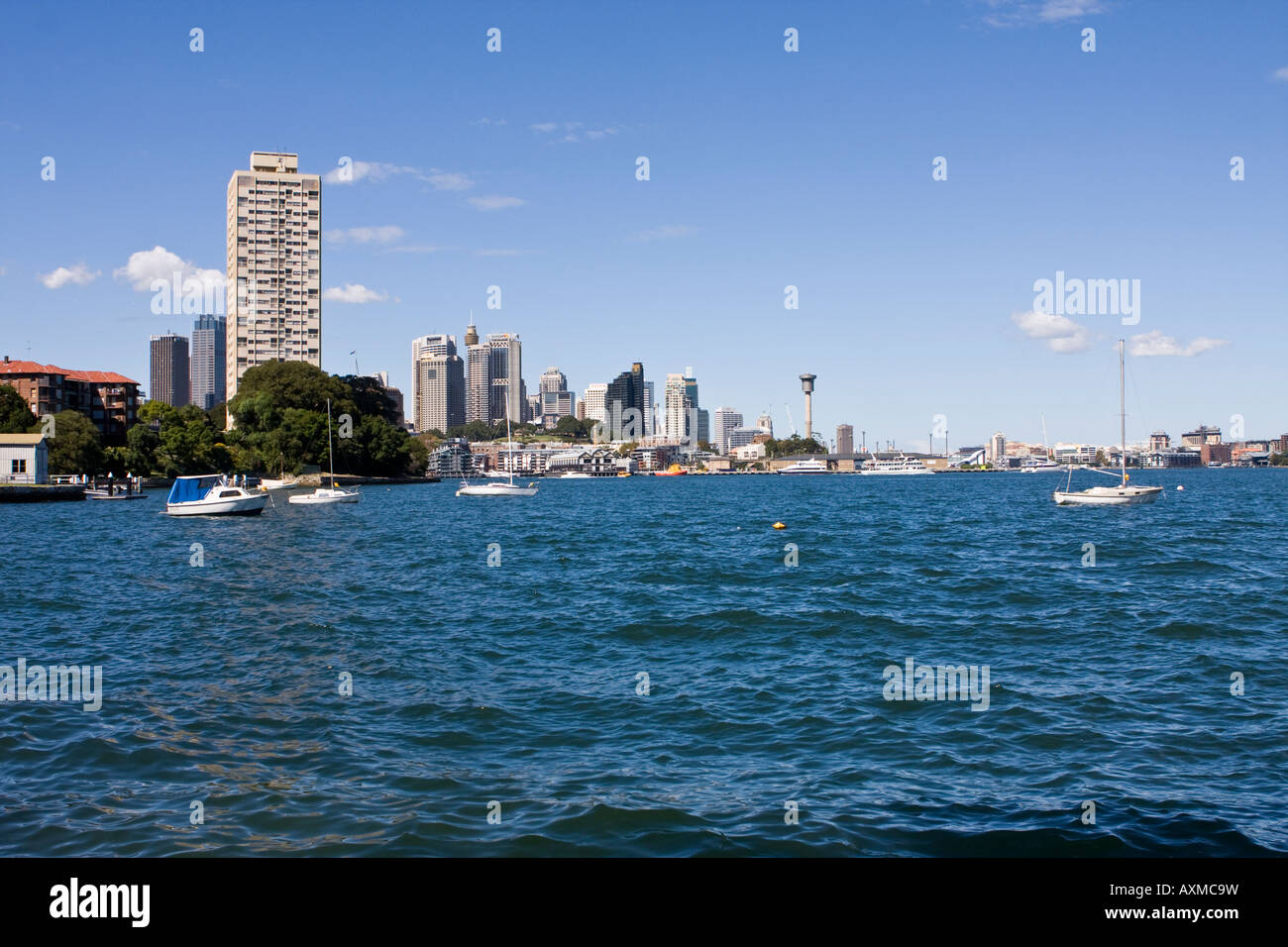 Sailboats bobbing at anchor in Berry's Bay with Blues Point Tower and the Sydney CBD in the background. Stock Photo