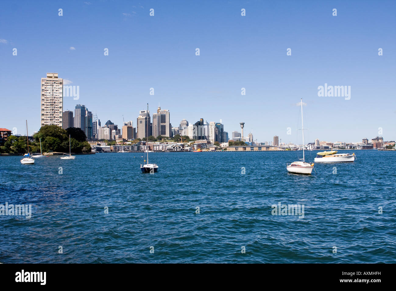 sailboats at anchor in Berry's Bay with blues point Tower and the Sydney CBD in the background Stock Photo