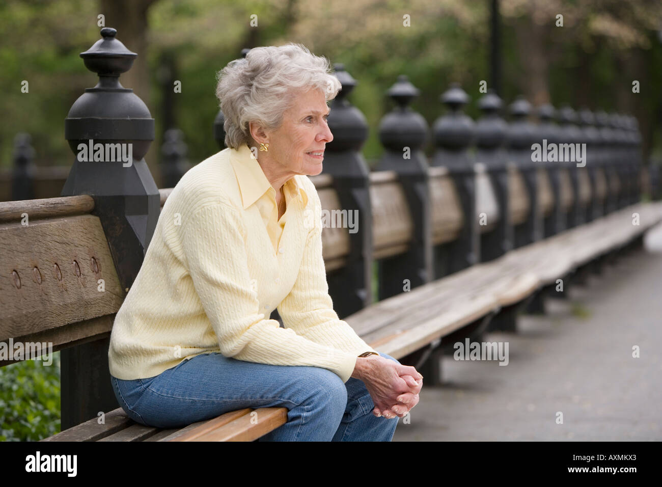 Portrait of woman sitting on park bench Stock Photo - Alamy
