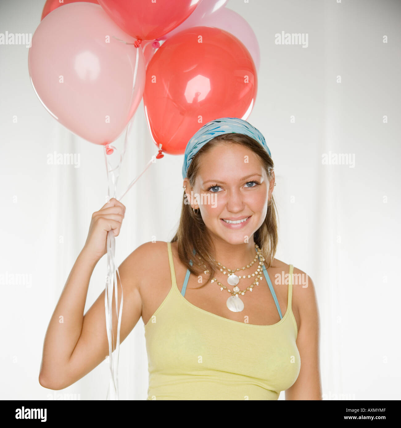 Young woman smiling and holding bunch of balloons Stock Photo