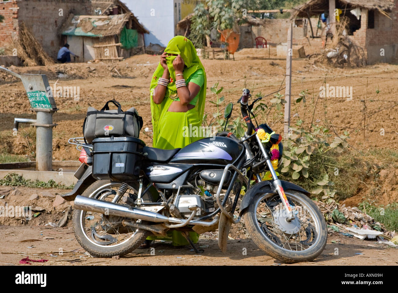 Rajasthani woman standing next to a motorcycle covering her face, India ...