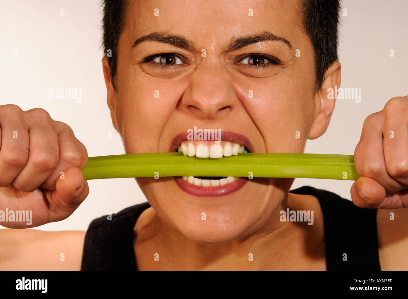 Studio portrait of woman biting a celery stalk Stock Photo