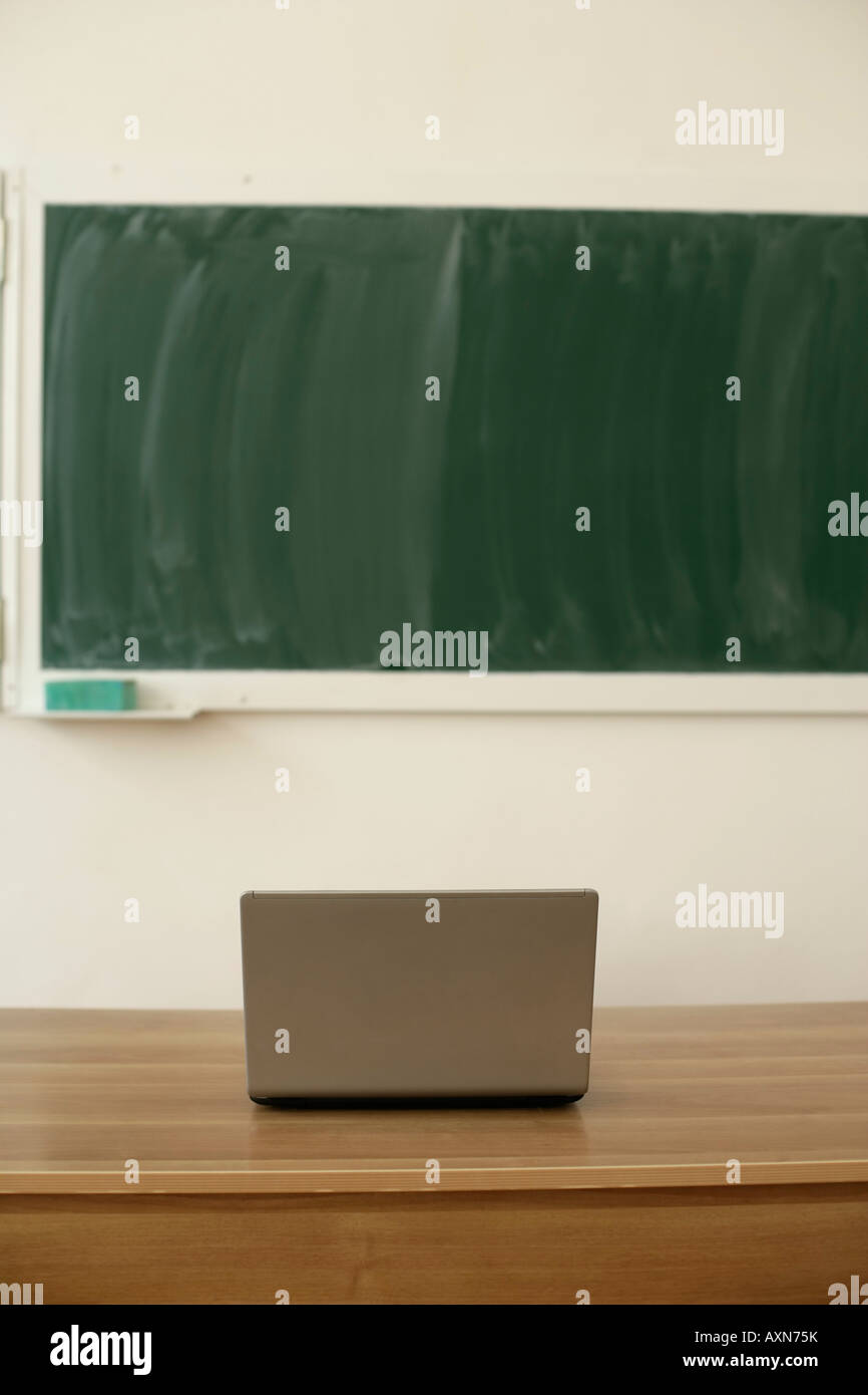 Laptop on a table, blackboard in background Stock Photo
