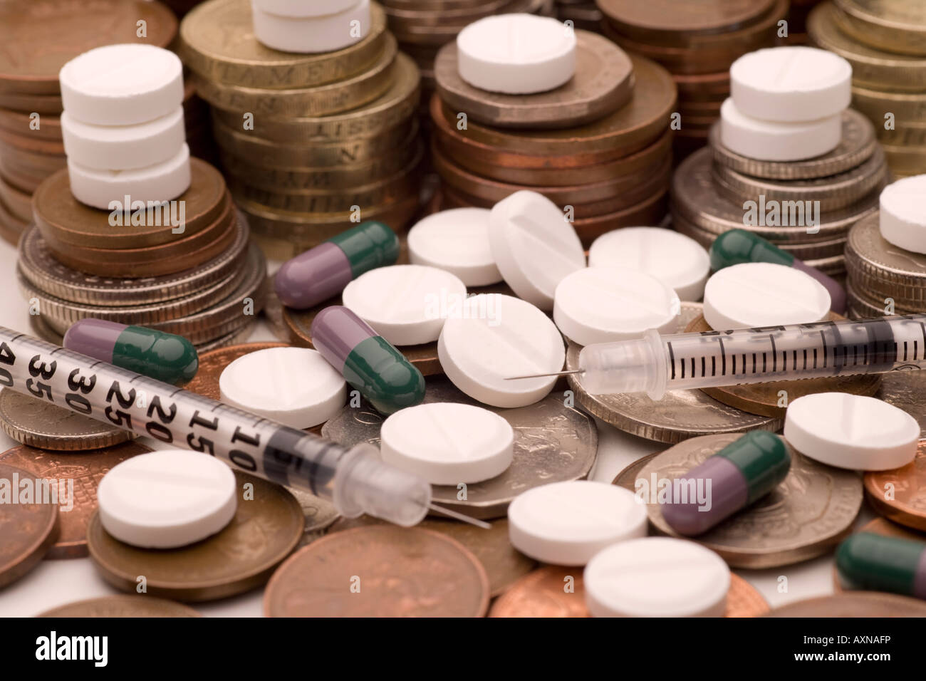 Pharmaceutical companies making huge profits out of healthcare products drugs coins and syringes Stock Photo