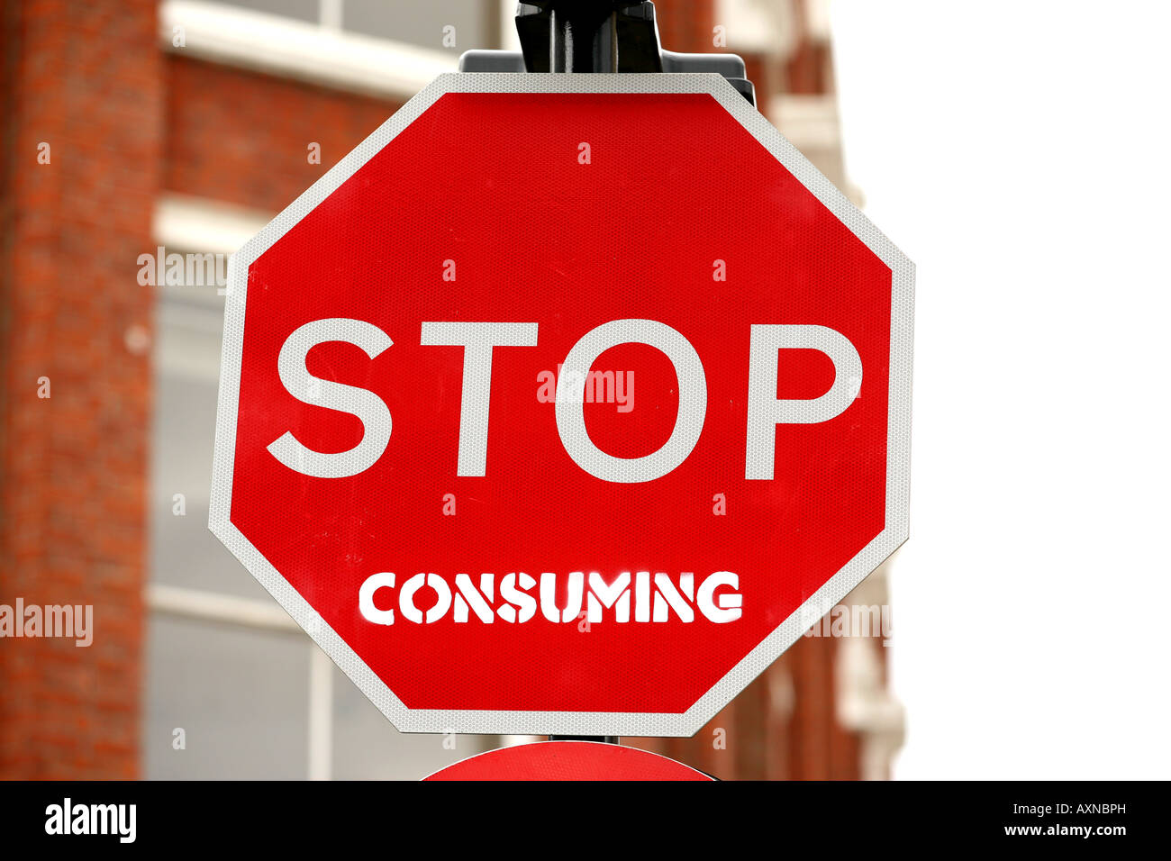a road traffic sign saying stop with graffiti saying consuming stop consuming Stock Photo