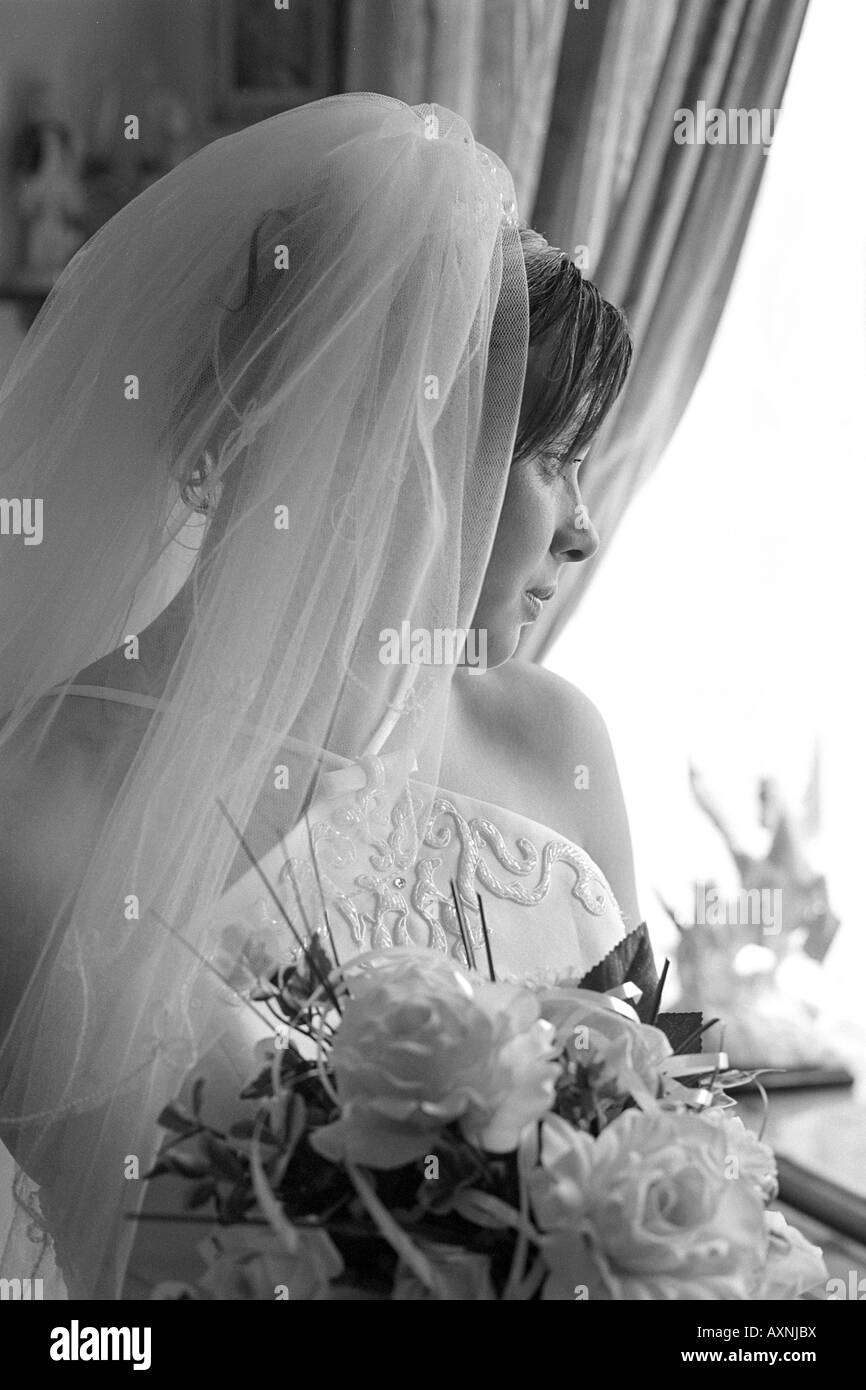 Bride sits alone gazing out of window Stock Photo