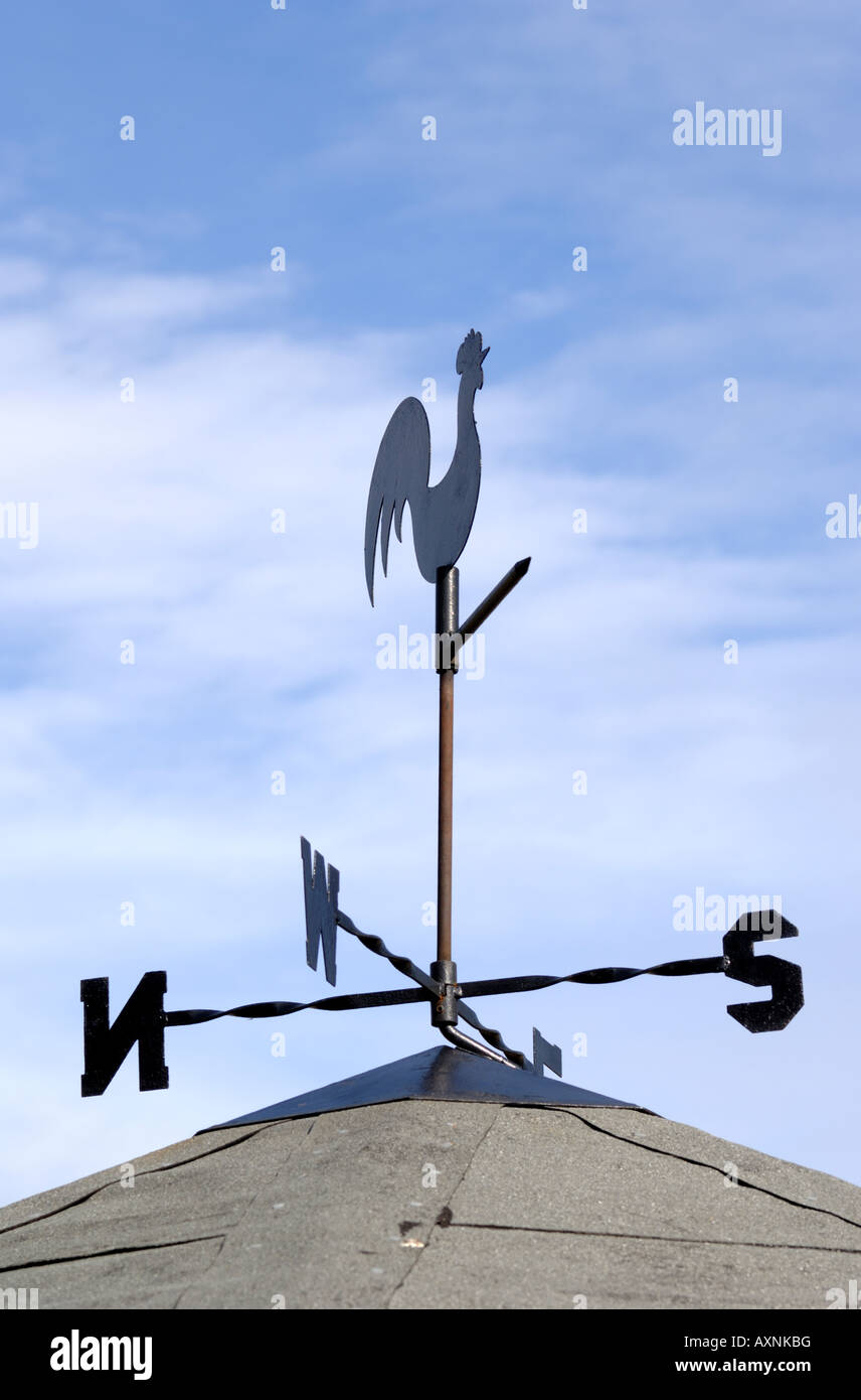 cockerel weathervane on roof against blue sky and light cloud Stock