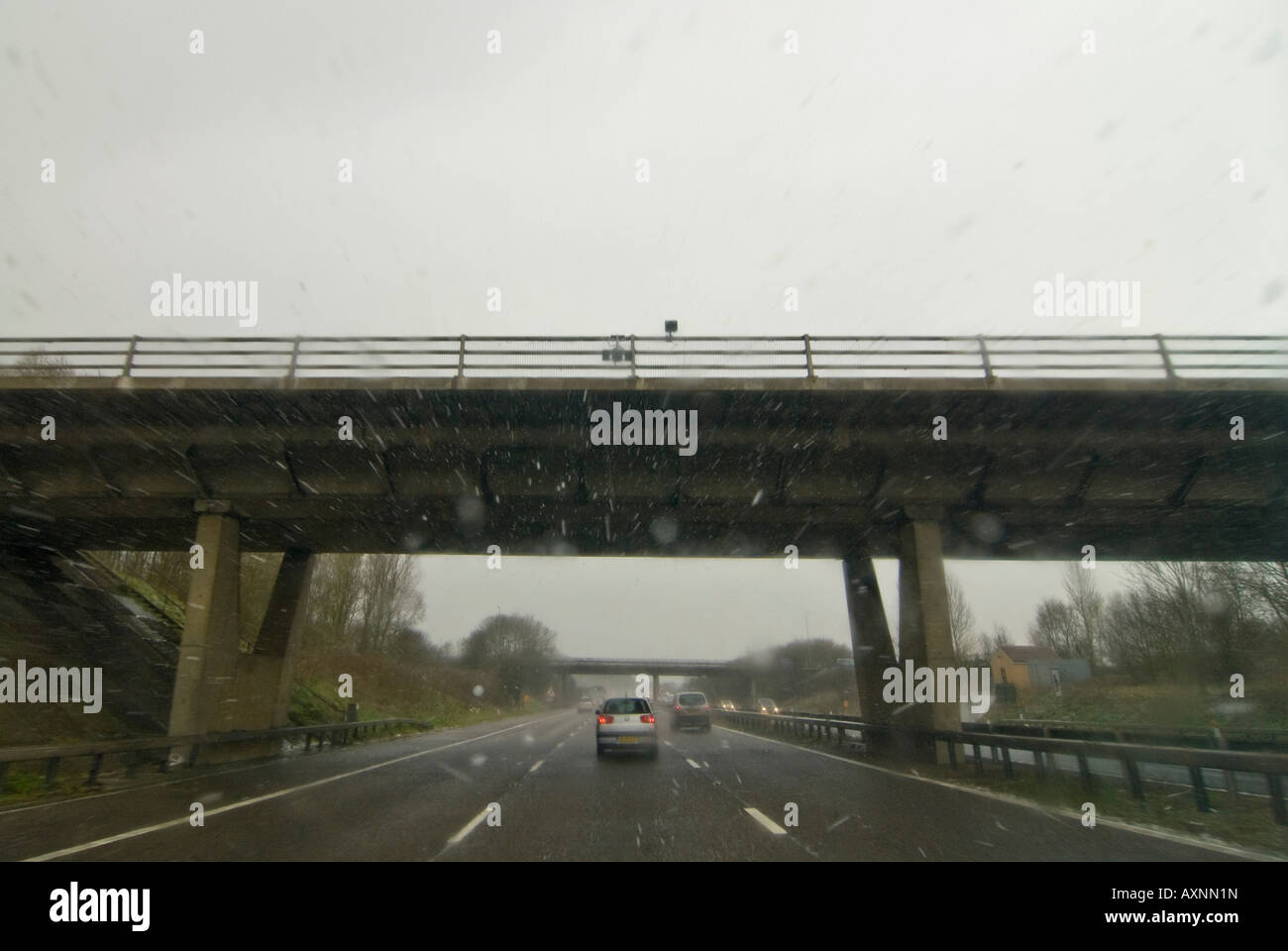 Horizontal wide angle view driving down the motorway in bad weather conditions - rain, sleet and snow. Stock Photo