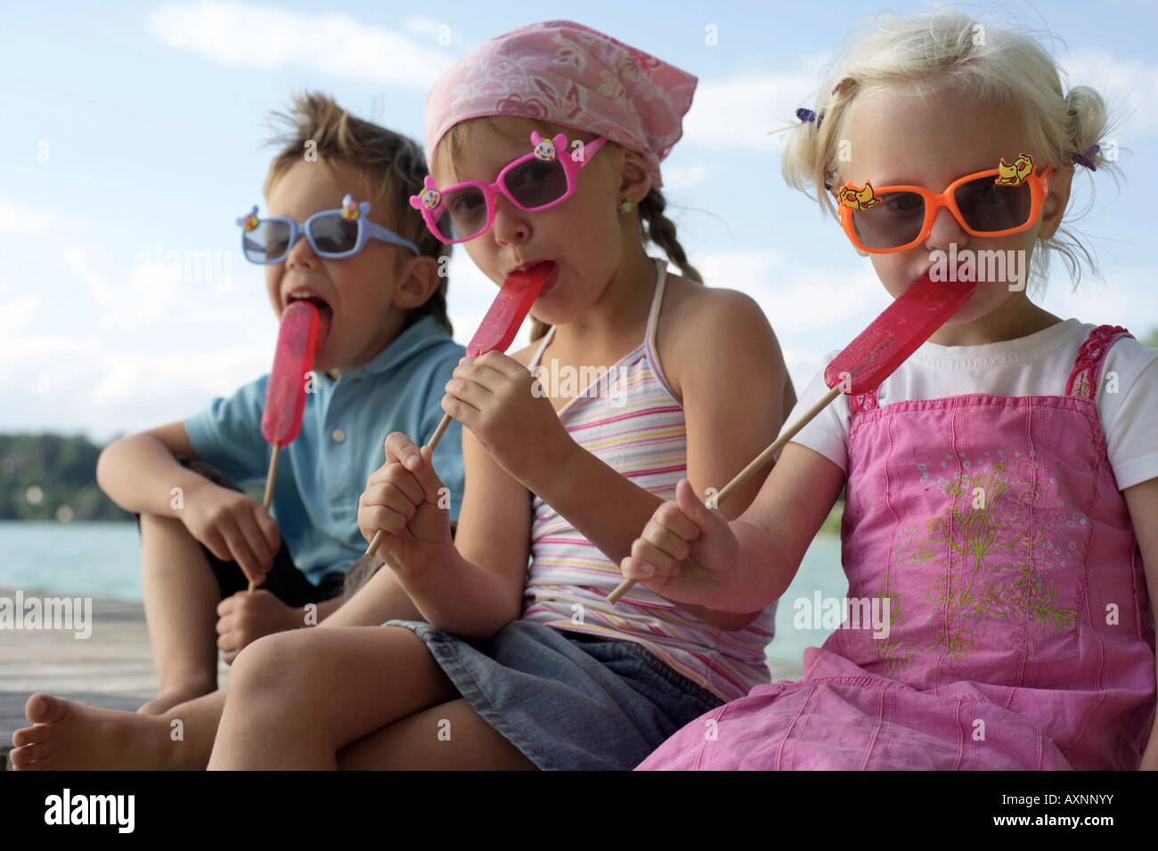 Three children with sunglasses each eating an ice lolli , close-up Stock Photo