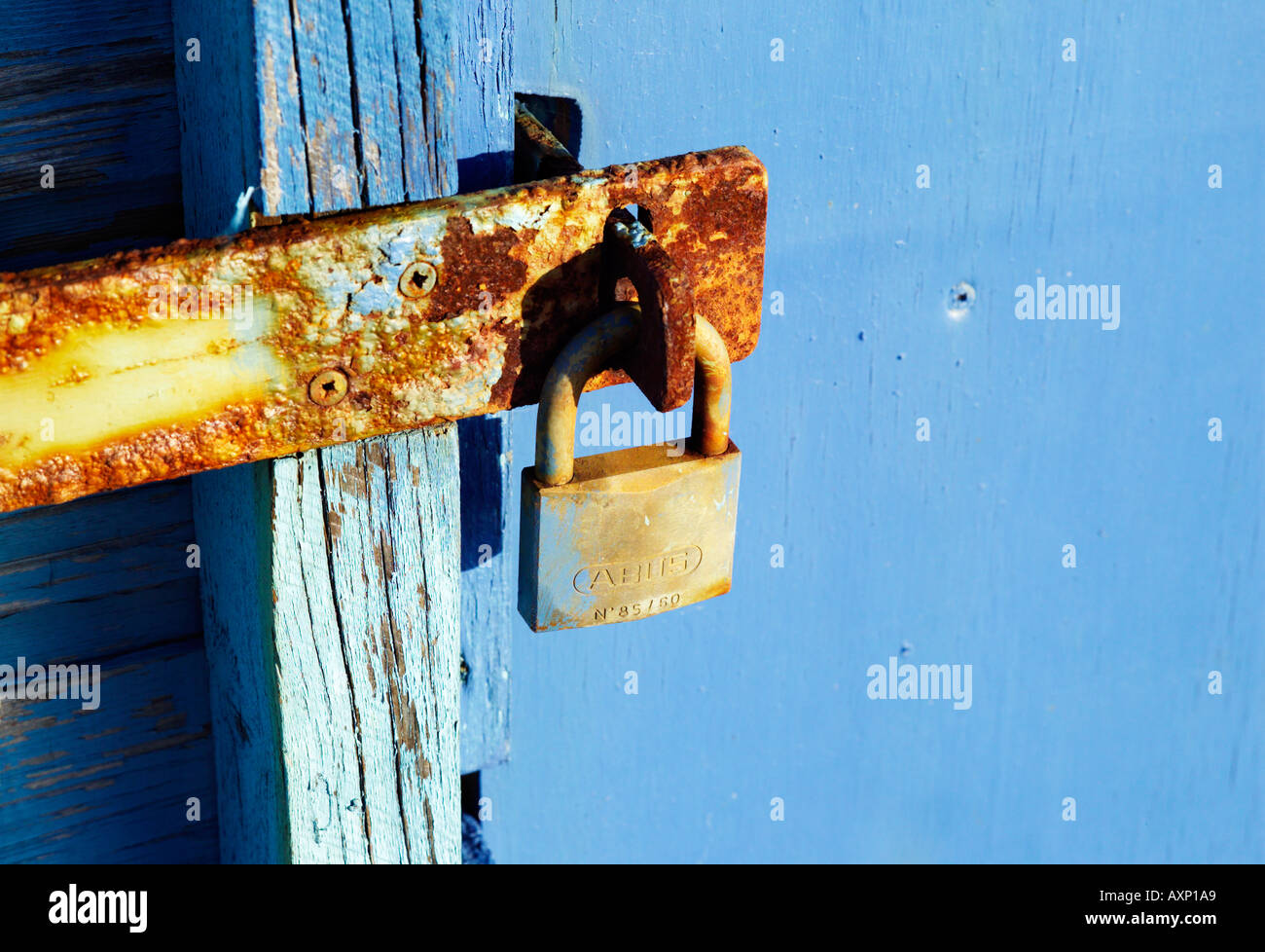 A padlock on the end of a rusty metal used to lock up a beach hut Stock Photo