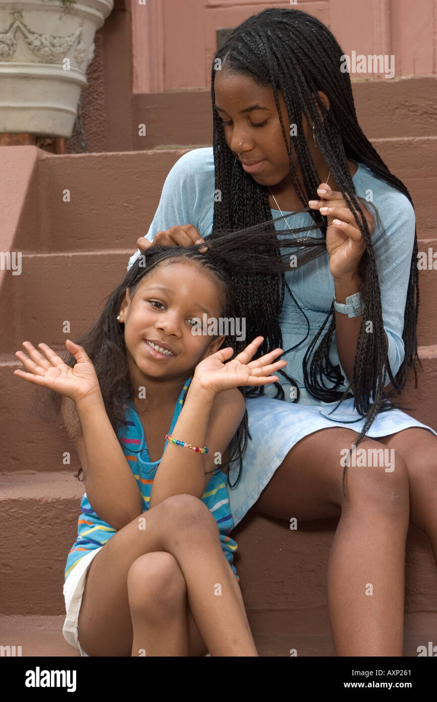 Teenage African American Girl Sitting On Steps And Braiding Hair