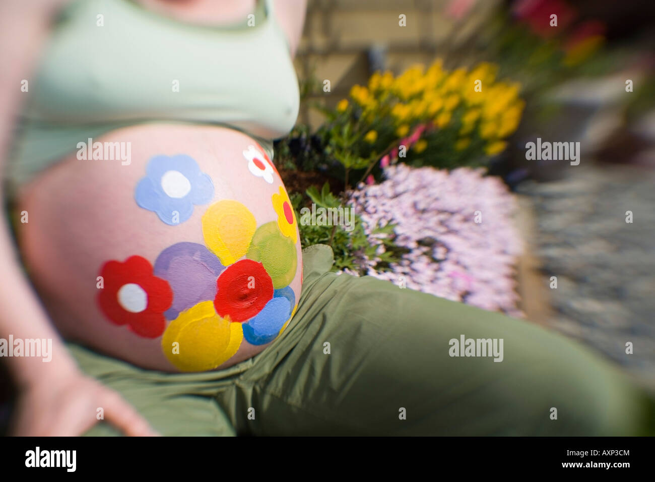 Pregnant Woman Sitting In Garden With Flowers Painted On Her Stomach Stock Photo Alamy