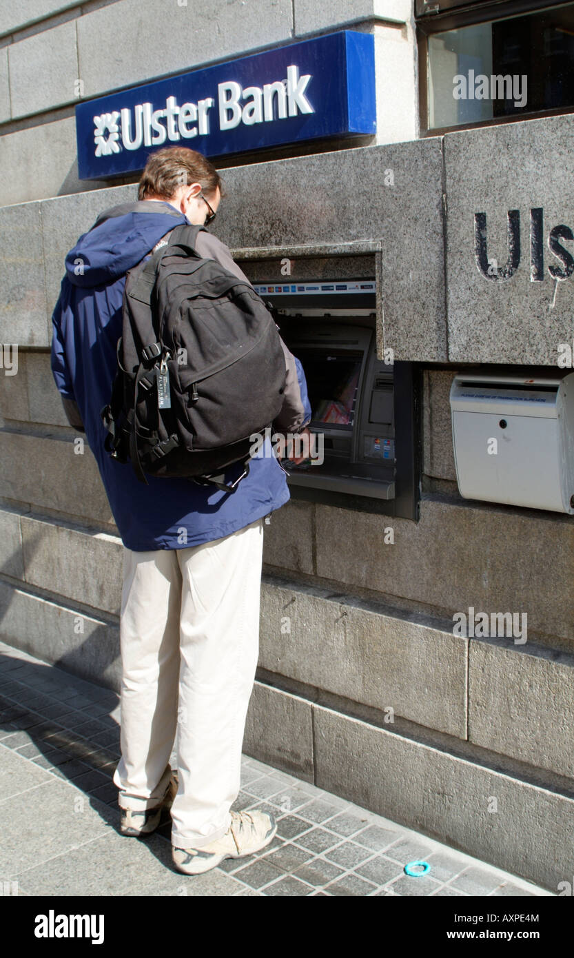 Man Using Hole in the Wall Cash Dispenser Machine at Ulster bank in Dublin Stock Photo