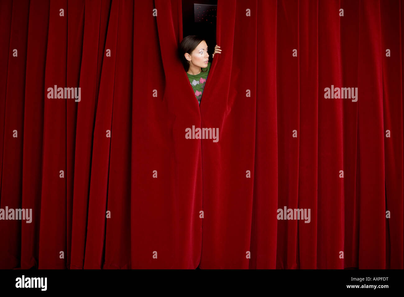 woman appearing from the back of a red curtain Stock Photo