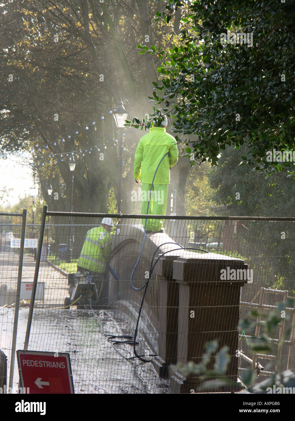 Workers cleaning off a concrete bridge with a high powered jet washer